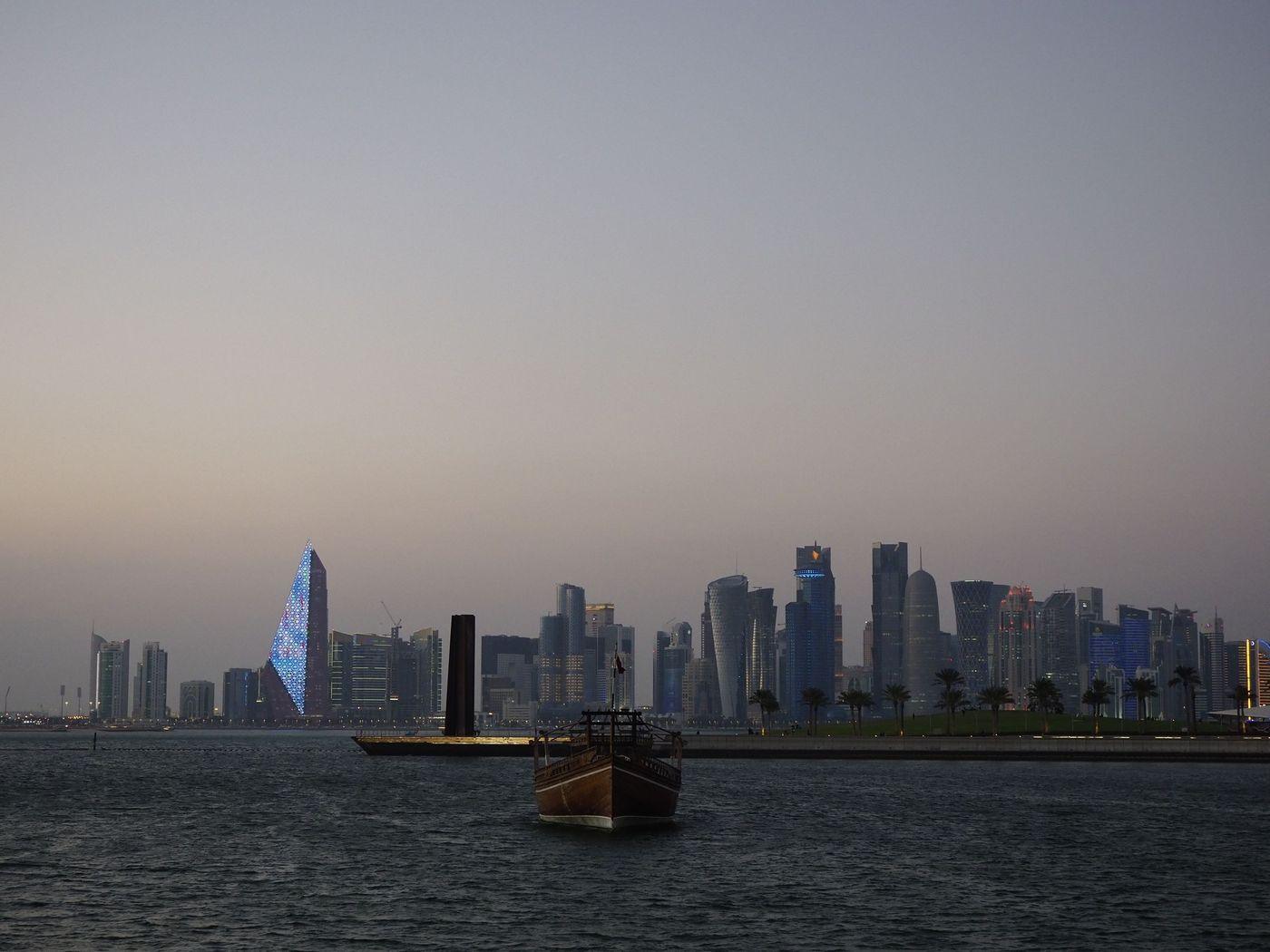 High-rise towers along a Gulf city waterfront reflected in calm water at dusk